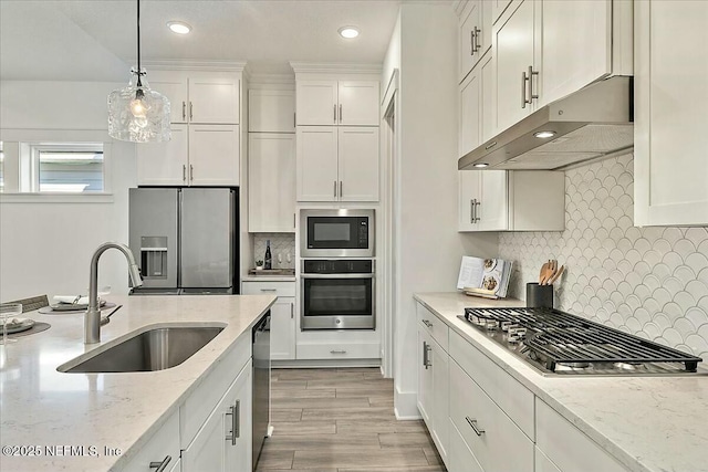 kitchen featuring under cabinet range hood, white cabinets, appliances with stainless steel finishes, and a sink