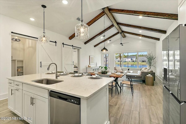 kitchen featuring a sink, white cabinets, stainless steel dishwasher, a barn door, and open floor plan