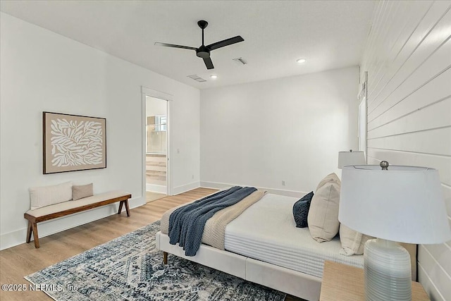 bedroom featuring ceiling fan, visible vents, baseboards, and wood finished floors