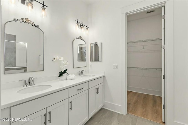 full bath with a spacious closet, visible vents, and a sink