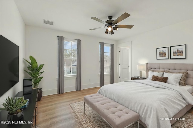 bedroom featuring a ceiling fan, light wood-style floors, visible vents, and baseboards