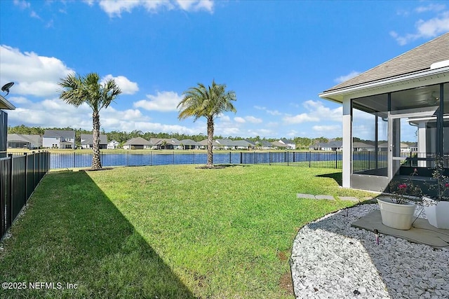 view of yard with a residential view, a water view, a sunroom, and fence