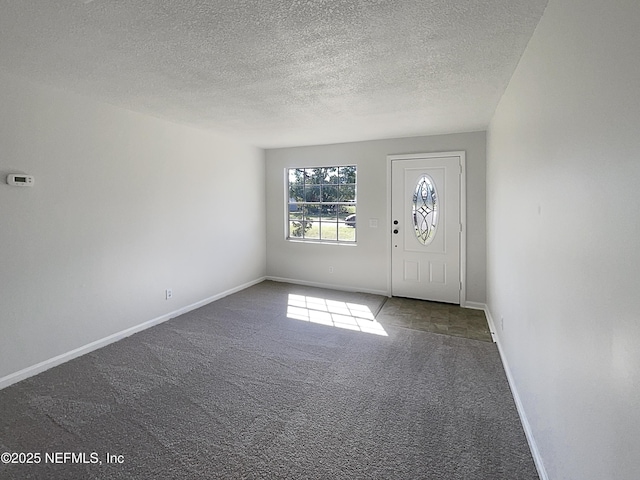 entryway featuring a textured ceiling, carpet, and baseboards