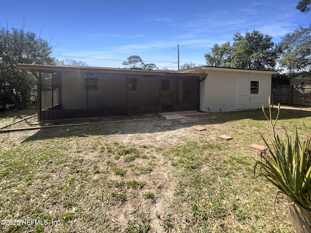 back of property with a sunroom, a yard, and fence