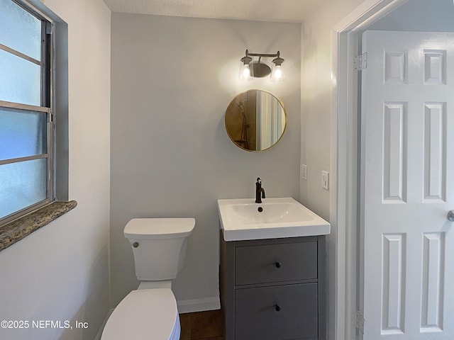 bathroom featuring toilet, baseboards, and vanity