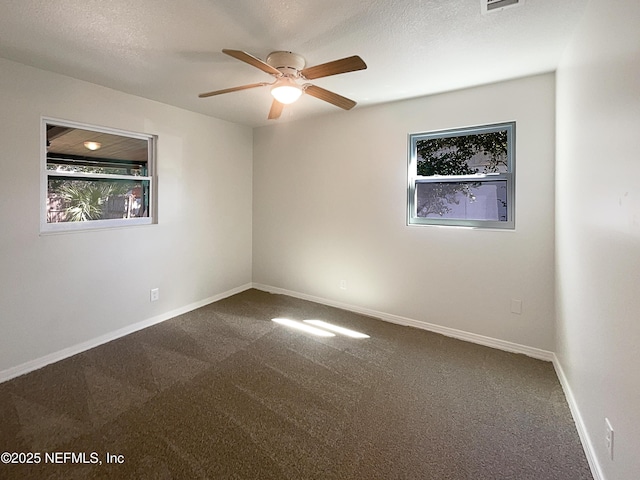 carpeted spare room featuring a textured ceiling, ceiling fan, visible vents, and baseboards