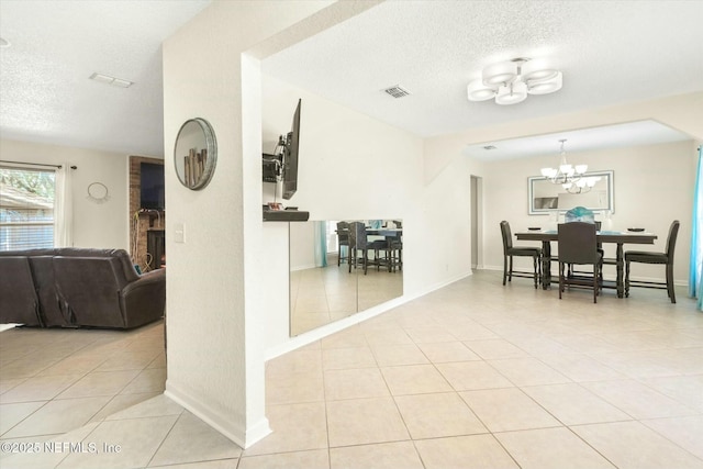 dining space featuring a textured ceiling, a notable chandelier, visible vents, baseboards, and tile patterned floors