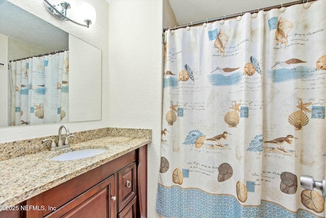 bathroom featuring a textured ceiling, curtained shower, and vanity