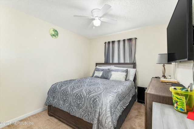 bedroom with ceiling fan, baseboards, a textured ceiling, and light colored carpet