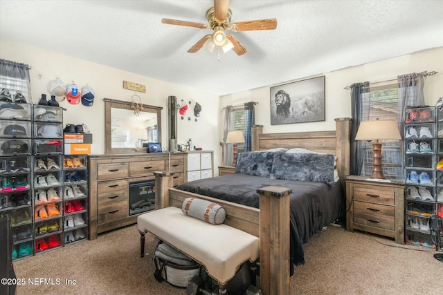 carpeted bedroom featuring ceiling fan and a textured ceiling