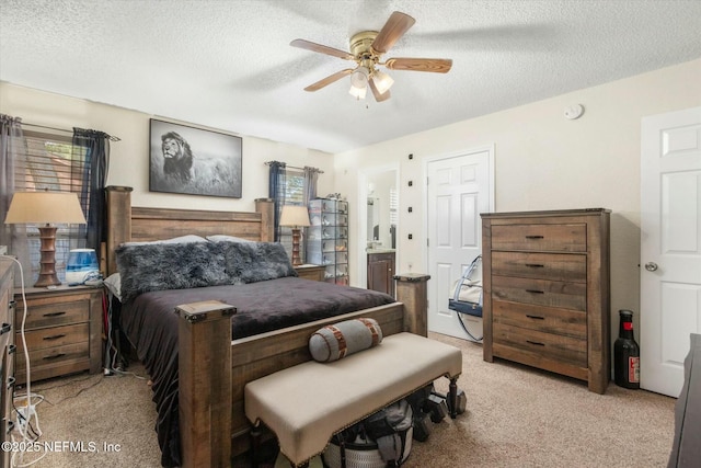 bedroom with light carpet, ensuite bath, ceiling fan, and a textured ceiling