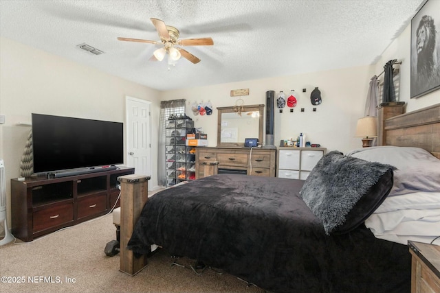 bedroom with a ceiling fan, carpet, visible vents, and a textured ceiling