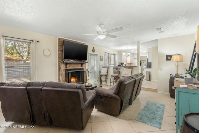 living area featuring a large fireplace, light tile patterned floors, a textured ceiling, and visible vents