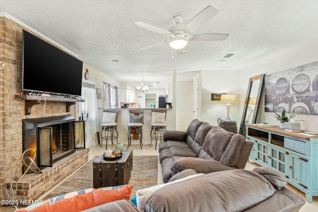 living area with light tile patterned floors, visible vents, a brick fireplace, a textured ceiling, and ceiling fan with notable chandelier