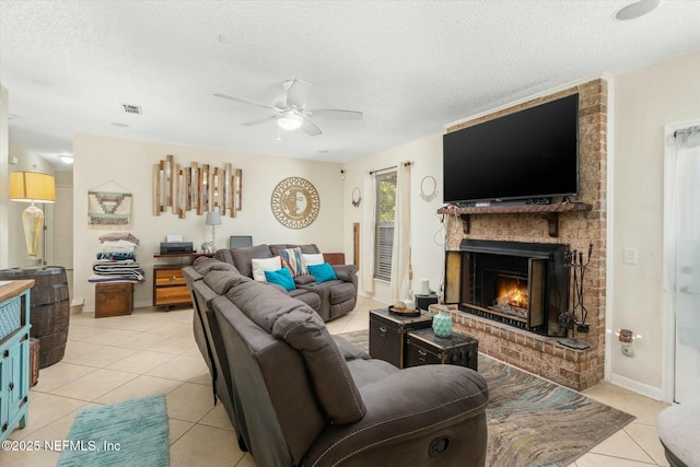 living area featuring a fireplace, light tile patterned floors, visible vents, a ceiling fan, and a textured ceiling