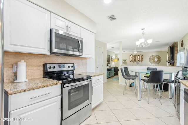 kitchen with visible vents, backsplash, appliances with stainless steel finishes, white cabinetry, and light tile patterned flooring