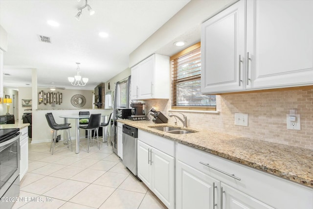 kitchen with light tile patterned floors, a sink, white cabinetry, appliances with stainless steel finishes, and tasteful backsplash