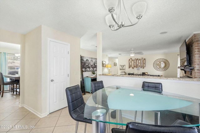 dining room with light tile patterned flooring, a textured ceiling, baseboards, and ceiling fan with notable chandelier