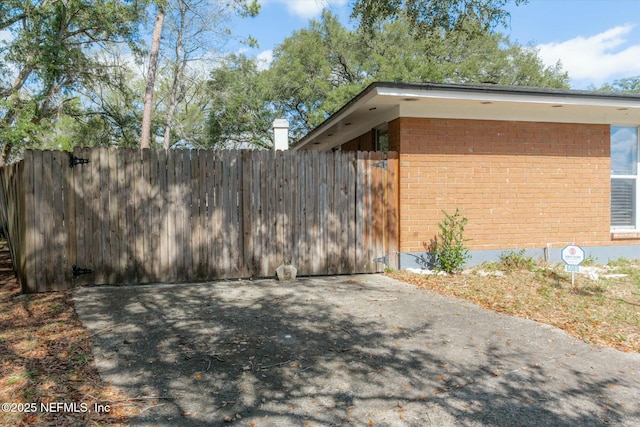 view of side of property with brick siding and fence