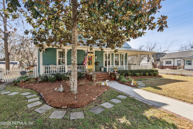 view of front of home with covered porch, metal roof, a front yard, and fence