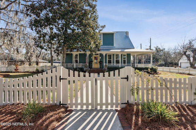 view of front of home with a fenced front yard, a gate, covered porch, and metal roof