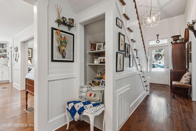 corridor featuring visible vents, built in features, dark wood-style floors, stairs, and a notable chandelier