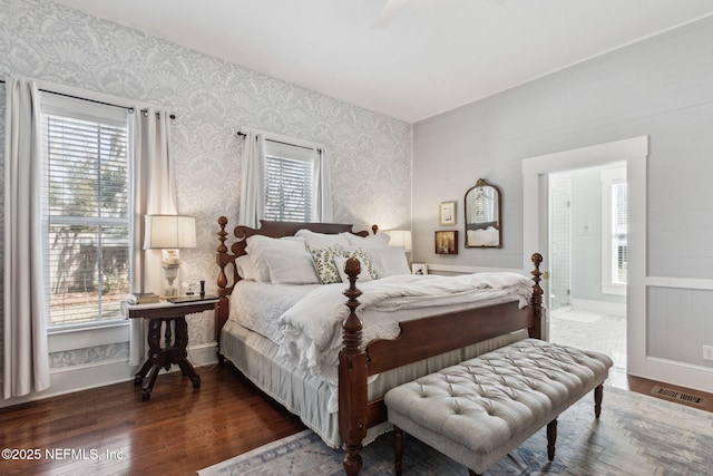 bedroom with baseboards, dark wood-type flooring, visible vents, and wallpapered walls