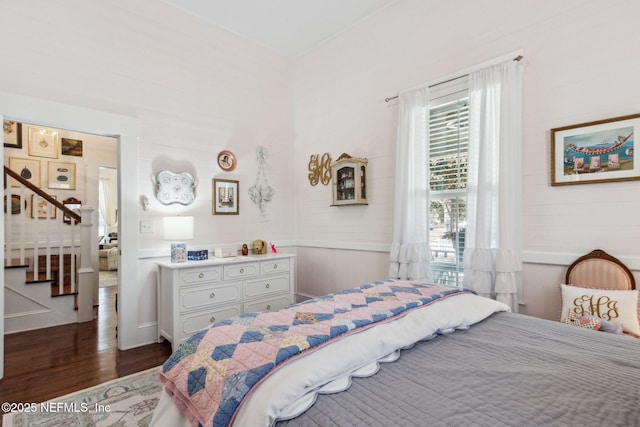 bedroom with a wainscoted wall and dark wood-type flooring