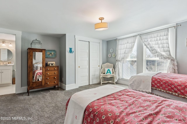 carpeted bedroom with a closet, ensuite bath, and baseboards