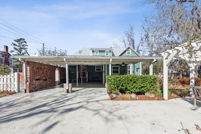 bungalow-style home featuring an attached carport, brick siding, driveway, and fence