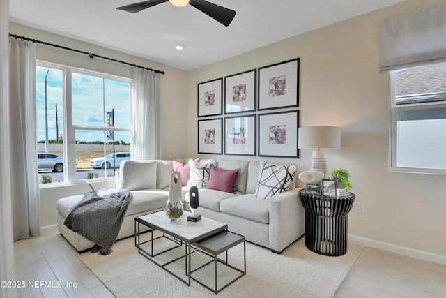 living area with ceiling fan, light wood finished floors, and baseboards