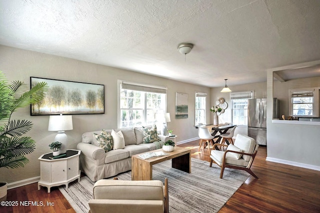 living room featuring wood finished floors, baseboards, and a textured ceiling