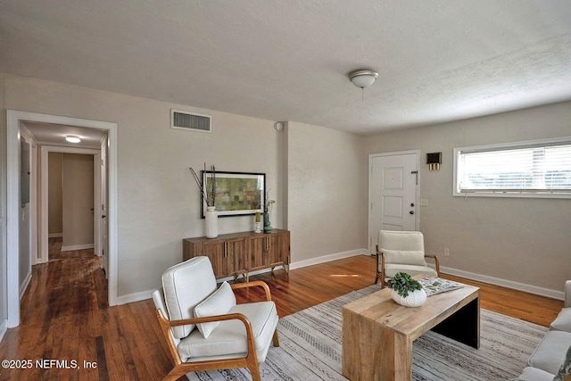 living area featuring wood finished floors, visible vents, and baseboards