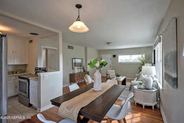 dining area featuring visible vents, light wood-style flooring, and baseboards