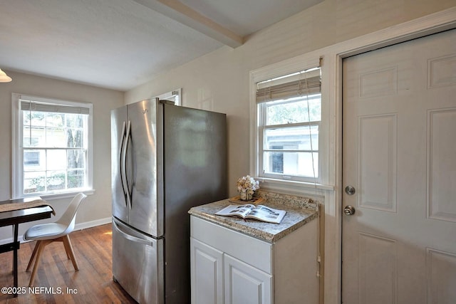 kitchen with beam ceiling, a healthy amount of sunlight, freestanding refrigerator, and wood finished floors