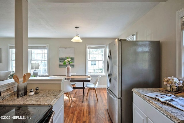 kitchen with a wealth of natural light, electric range, freestanding refrigerator, and wood finished floors