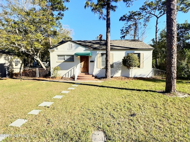 view of front of property with stucco siding, entry steps, a front yard, and fence