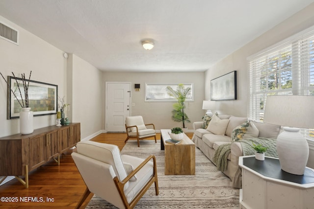 living room with visible vents, baseboards, and wood finished floors