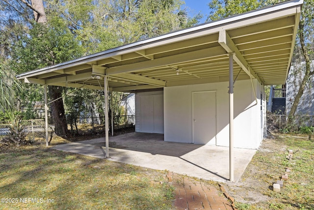 view of outdoor structure with a carport and fence