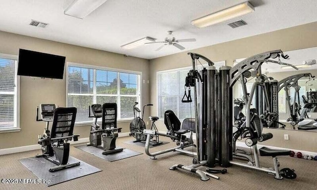 exercise room with baseboards, visible vents, and a ceiling fan