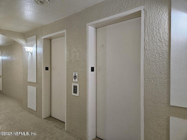 hall with arched walkways, a textured wall, and elevator