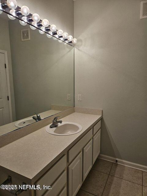 bathroom with tile patterned flooring, vanity, visible vents, and baseboards