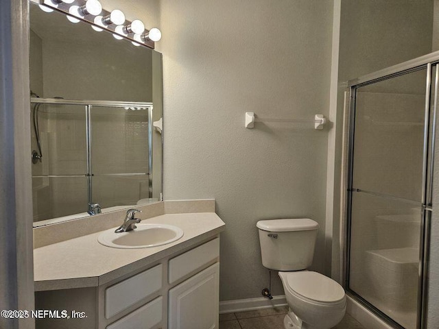 full bath featuring tile patterned flooring, tiled shower, vanity, and toilet