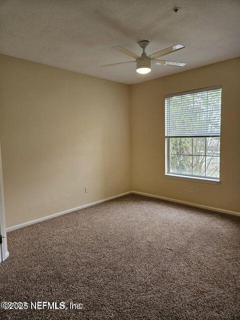 unfurnished room with carpet flooring, a textured ceiling, and baseboards