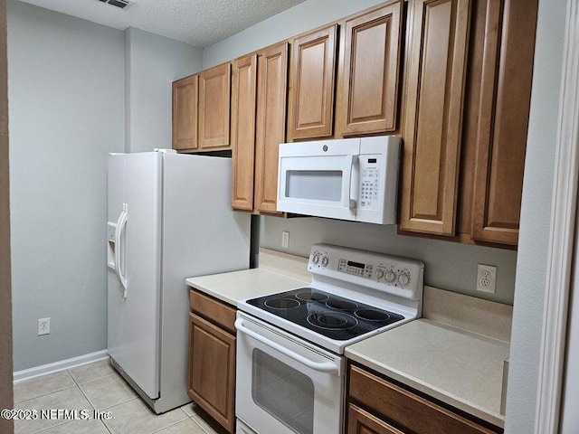 kitchen featuring brown cabinetry, white appliances, light countertops, and light tile patterned floors