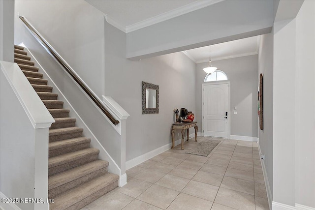 foyer entrance featuring light tile patterned floors, baseboards, stairway, and ornamental molding