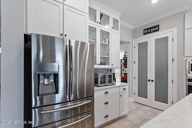 kitchen with glass insert cabinets, appliances with stainless steel finishes, french doors, white cabinetry, and light tile patterned flooring