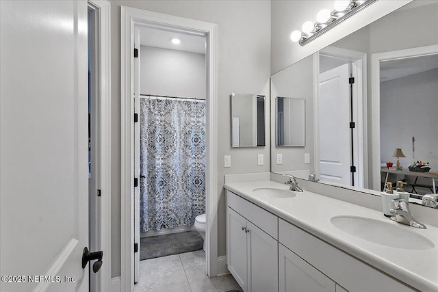 full bathroom with double vanity, tile patterned flooring, toilet, and a sink