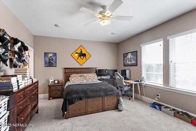 bedroom featuring baseboards, a textured ceiling, a ceiling fan, and light colored carpet