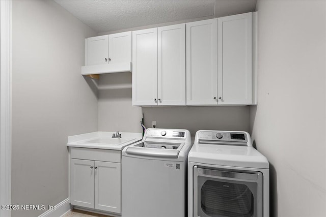 laundry room with a textured ceiling, a sink, baseboards, independent washer and dryer, and cabinet space